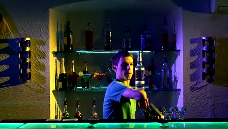 Young-bartender-making-professional-tricks-with-two-glasses,-shaker-and-bottle-standing-behind-the-bar,-catching-on-elbow,-throwing-up,-slow-motion