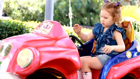 Muchacha-del-niño-y-monta-un-automóvil-eléctrico-en-el-parque-para-el-entretenimiento.