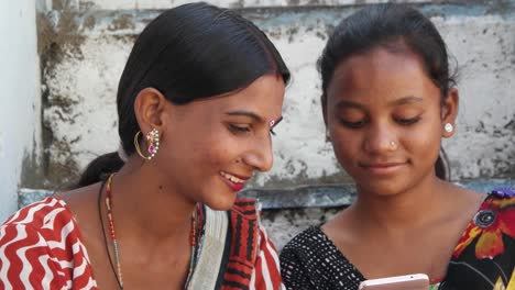 Extreme-closeup-of-females-Indian-on-a-smart-mobile-phone-device-and-listening-to-music-tapping-fingers-tilt-down-to-their-colorful-sari-print-pattern-design--art-costume-dress-ethnic-local-Indian