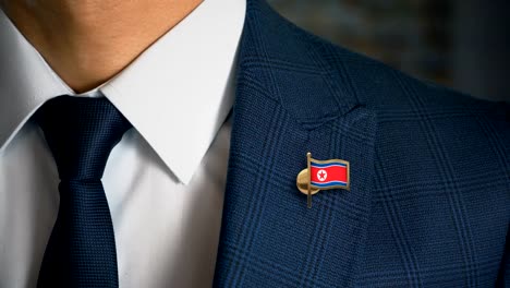 Geschäftsmann-zu-Fuß-in-Richtung-Kamera-mit-Land-Flagge-Pin---Nordkorea