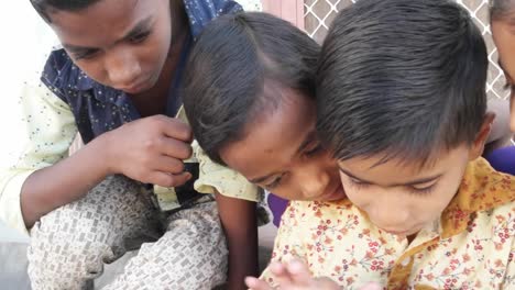 Indian-Kids-busy-on-a-touchscreen-tablet,-elder-sibling-teaching-them,-close-up-handheld