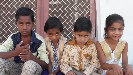 Indian-kids-with-their-heads-down-but-still-smiling-smugly,-handheld