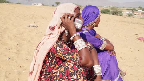 Freunde-sitzen-in-der-heißen-Sonne-der-Wüste-Pushkar-während-das-Kamel-fair-auf-dem-Handy