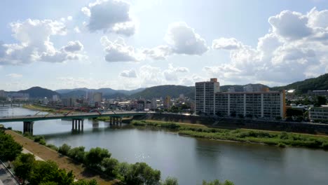 The-view-of-the-city-from-the-rooftop,-the-river-flowing-between-the-bridges,-the-sky-with-clouds-and-the-green-mountains,-the-apartment