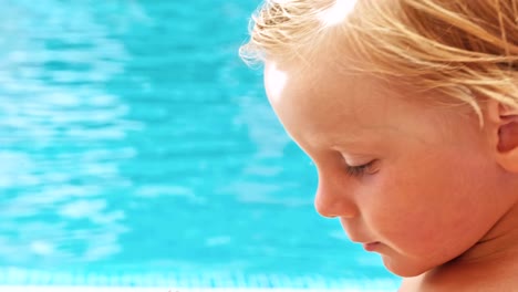 Happy-little-boy-sitting-near-the-pool