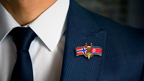 Geschäftsmann-zu-Fuß-in-Richtung-Kamera-mit-Freund-Flaggen-Pin-Norwegen---Nordkorea