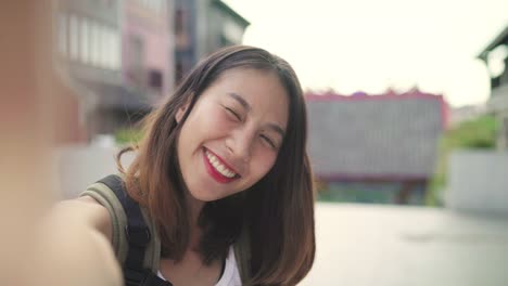 Mujer-de-blogger-alegre-hermosa-joven-asiático-para-mochileros-con-smartphone-tomando-selfie-mientras-viaja-a-Chinatown-en-Beijing,-China.-Estilo-de-vida-mochila-concepto-de-vacaciones-de-viajes-turísticos.-Punto-de-vista.