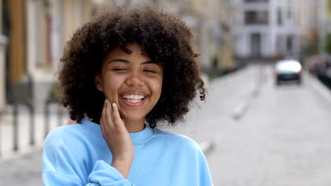 Outdoor-portrait-of-laughing-curly-mixed-race-girl