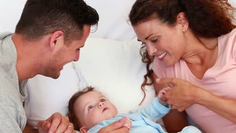 Baby-boy-being-tickled-by-parents-on-bed