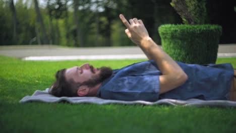 Man-ruht-mit-Smartphone-auf-dem-open-air