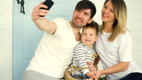 Father-of-happy-family-make-selfie-with-his-wife-and-little-son-in-front-their-home-door