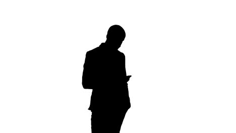 Silhouette-Young-man-in-suit-walking-and-sending-text-message-on-mobile-phone