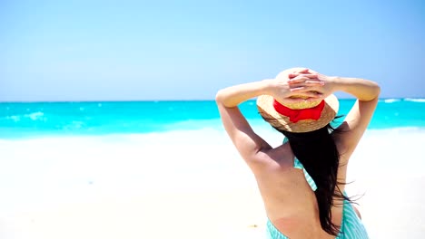 Rückansicht-der-schönen-Frau-im-Hut-auf-Sommerferien-am-weißen-Strand.