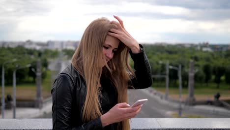 Cheerful-Young-Woman-Blonde-uses-a-smartphone.