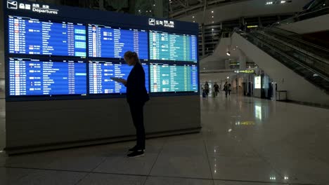 Frau-mit-Tablet-PC-von-Flugplan-am-Flughafen