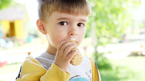 Ein-kleiner-Junge-von-drei-Jahren-ist-Eis-in-einer-Waffel-Tasse-Essen.