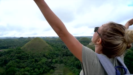 CÁMARA-lenta-mujer-viajando-brazos-extendidos-en-las-colinas-de-Chocolate-de-Bohol,-Filipinas