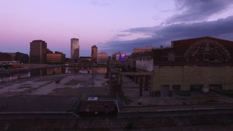 Aerial-shot-of-abandoned-building-i-Malmo-city-at-dusk.-Rundown-urban-industrial-area,-cityscape-and-office-buildings-in-the-background