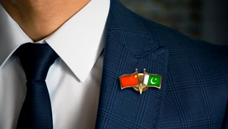 Geschäftsmann-zu-Fuß-in-Richtung-Kamera-mit-Freund-Land-Flaggen-Pin-China---Pakistan