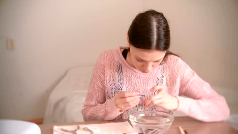 Woman-remove-cuticle-with-pusher.-Makes-manicure-herself.-Manicure-tools-on-the-table.