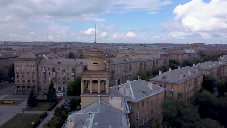 Drone-en-vuelo-cerca-de-la-torre-de-estilo-antiguo-con-fábrica-en-el-fondo