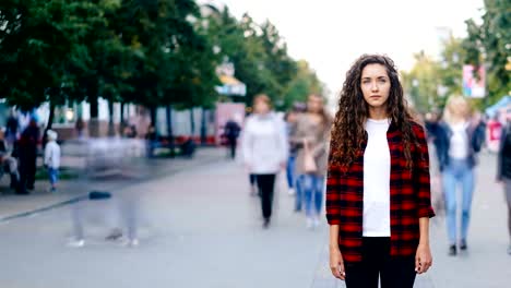 Time-lapse-retrato-de-mujer-joven-confedent-solas-en-la-calle-en-día-de-verano-y-mirando-a-cámara-mientras-personas-están-zumbando-alrededor-de-prisa.