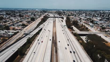 Zánganos-sobrevolando-adelante-grande-transitada-carretera-interestatal-americana-con-puentes-y-pasos-elevados,-los-coches-se-mueven-en-todas-las-direcciones.