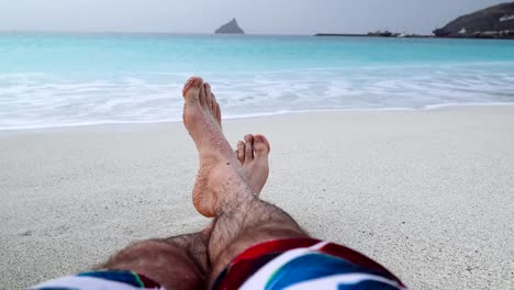 Mans-feet-on-sandy-beach.-Vacation-and-relaxation-concept,-beach-holidays-background.-4k-video