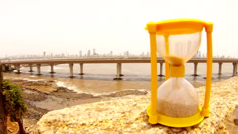 Bandra-Worli-Sea-Link-Mumbai-in-front-small-sandglass-sand-quickly-fall-hand-turns-it