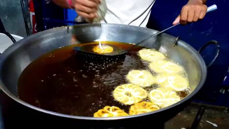 Braten-von-Jalebi-in-Zuckersirup-in-einem-süßen-Snack-Shop.-Jalebi-ist-eine-berühmte-indische-gebratene-Süßigkeit.