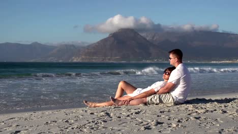 Couple-sitting-in-romantic-embrace-on-beach,-Cape-Town,South-Africa