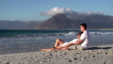 Pareja-sentada-en-la-romántica-abrazar-en-la-playa,-Ciudad-del-Cabo,-Sudáfrica