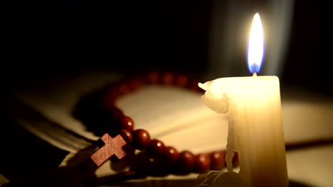 Candle-burning-on-the-background-of-the-holy-book-and-a-cross
