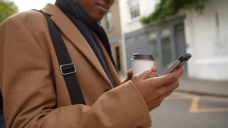 Nahaufnahme-von-junger-Mann-mit-Handy-auf-belebten-Stadt-Straße