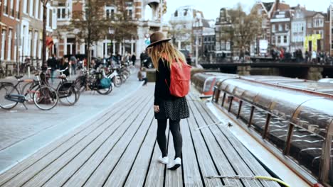 Young-European-lady-walks-talking-on-the-phone.-Free-and-easy-relaxed-walk-along-wooden-river-embankment-with-a-boat.-4K