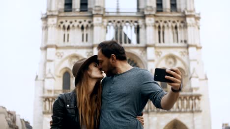 Glückliches-junges-Paar-stehen-in-der-Nähe-von-Notre-Dame-in-Paris.-Frankreich-und-unter-Selfie-Fotos-auf-smartphone