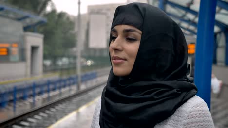 Young-dreaming-muslim-woman-in-hijab-is-waiting-for-train,-religion-concept,-urban-concept