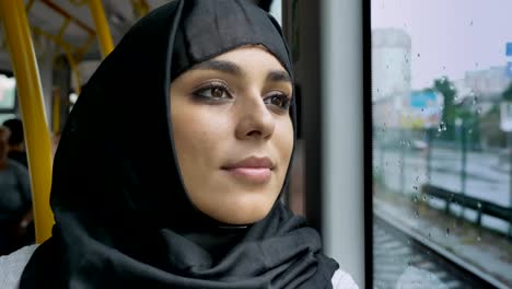 Joven-musulmana-de-dulce-en-hijab-es-ver-en-ventana-lluviosa-en-autobús,-concepto-de-transporte,-concepto-urbano,-concepto-de-tiempo,-soñando-con-concepto