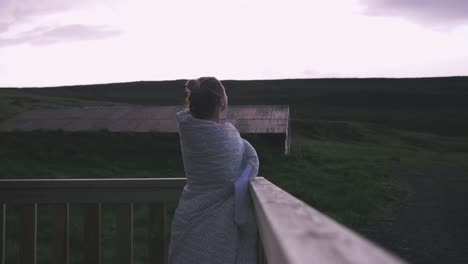 Junge-Frau-in-Decke-Stand-auf-dem-Balkon,-die-Aussicht-auf-dramatische-Wolken-Nahaufnahme-Schuss