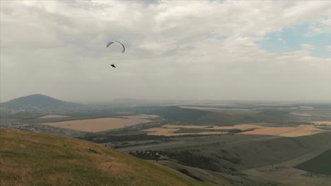 Athlet-Gleitschirm-fliegt-auf-seinem-Gleitschirm-neben-die-Schwalben.-Follow-up-Aufnahmen-aus-der-Drohne