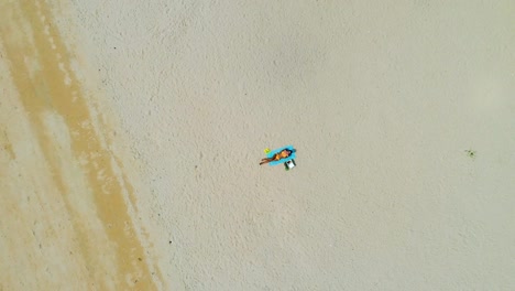 Top-view-drone-shot-of-woman-relaxing-at-the-beach-in-summer