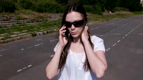 Young-woman-talking-mobile-phone-walking-in-stadium.