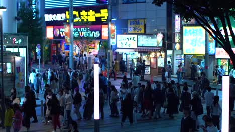 EDITORIAL-Film:-High-Angle-Aufnahme-von-der-viel-befahrenen-Straße-der-großen-Stadt-mit-Massen-von-Menschen-am-Abend-zu-Fuß-bewegen.-Werbetafeln-glühen.-Tokio-bei-Nacht.