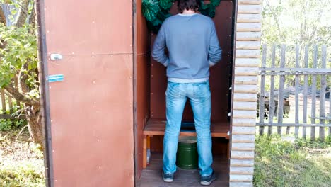 Mann-pisst-in-Außentoilette-mit-einem-Topf-im-Dorf.