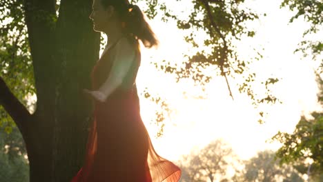 Happy-girl-dancing-on-green-field,-beautiful-red-dress,-light-dress-fly-in-air