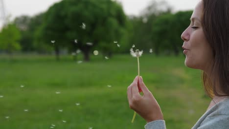 Portrait-of-woman-blow-on-dandelion,-slow-motion