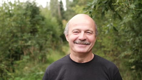 happy-senior-caucasian-man-walking-outside-in-park-by-trees.