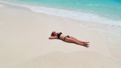 Gorgeous-woman-basks-on-sand-tongue-surrounded-by-turquoise-water