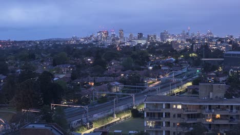 Tren-de-la-línea-en-Chatswood-NSW-con-la-ciudad-de-Sydney-en-el-lapso-de-tiempo-de-fondo-tiempo-de-Crepúsculo