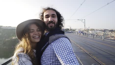Happy-couple-taking-selfie-on-bridge